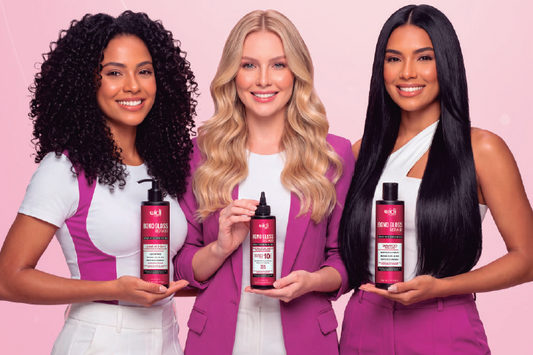Women with long straight, wavy and curly hair against a soft pink wall, representing glossy care for damaged and porous hair